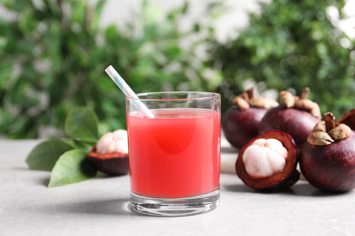 Delicious mangosteen juice in glass on light table