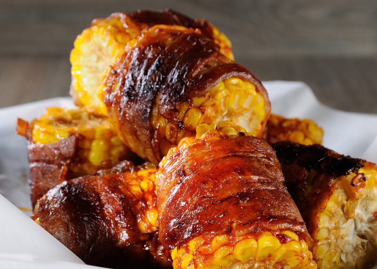 Grilled corn wrapped with bacon slices under BBQ sauce