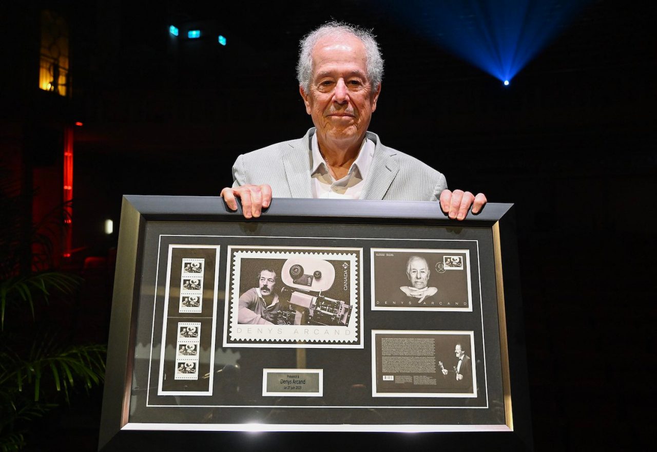Filmmaker Denys Arcand poses with a Canada Post stamp in his honour in Montreal, Tuesday, June 27, 2023. THE CANADIAN PRESS/Graham Hughes