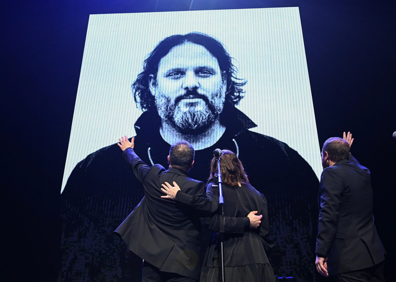 Members of Les Cowboys Fringants wave to a photograph  during an event paying tribute to the late Karl Tremblay, lead singer of the ban, in Montreal, Tuesday, November 28, 2023. THE CANADIAN PRESS/Graham Hughes