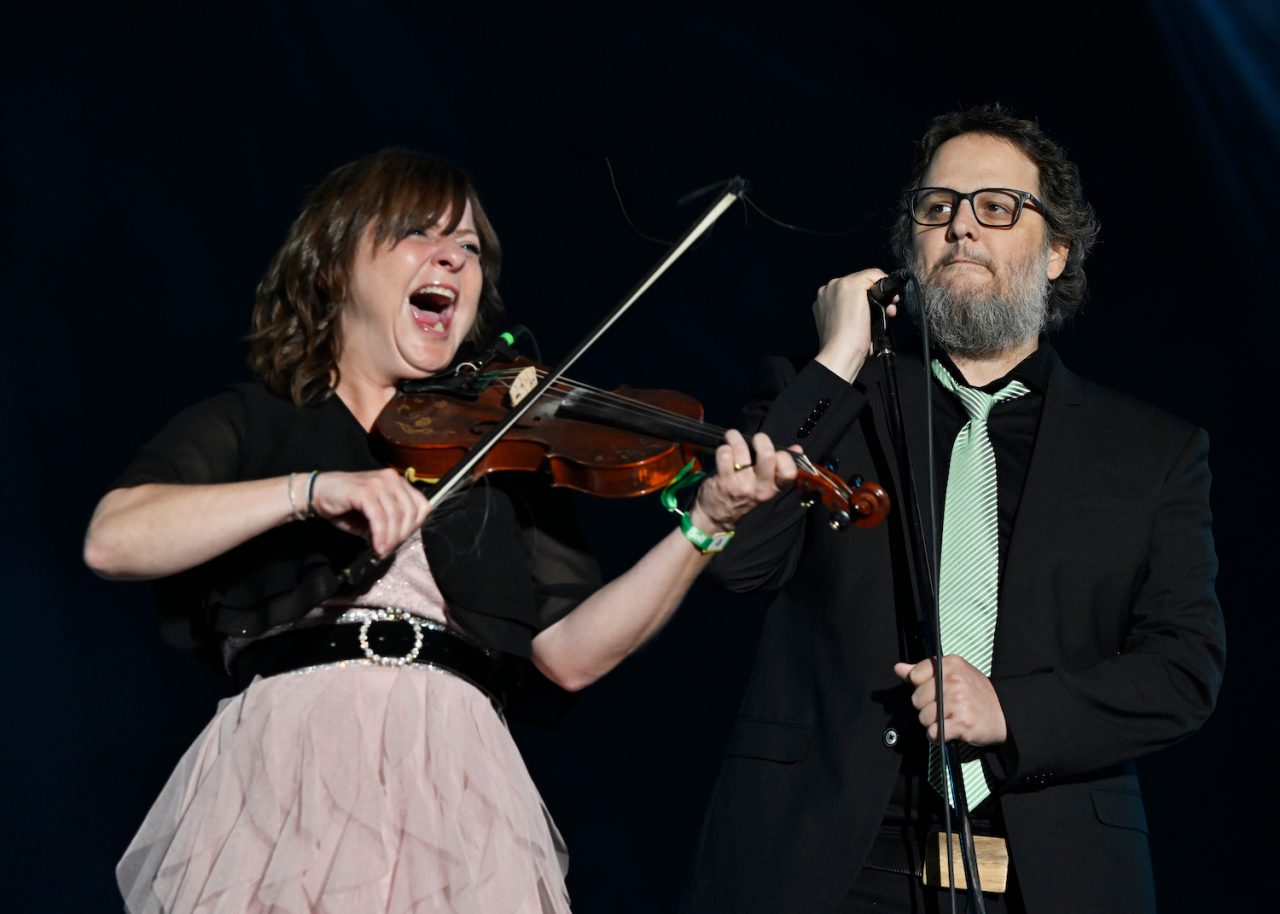 Les Cowboys Fringants lead singer Karl Tremblay, right, walks on stage as his wife Marie-Annick Lepine plays the violin during their performance at the Quebec Summer Festival, in Quebec City, Monday, July 17, 2023. Tremblay is currently battling cancer. THE CANADIAN PRESS/Jacques Boissinot