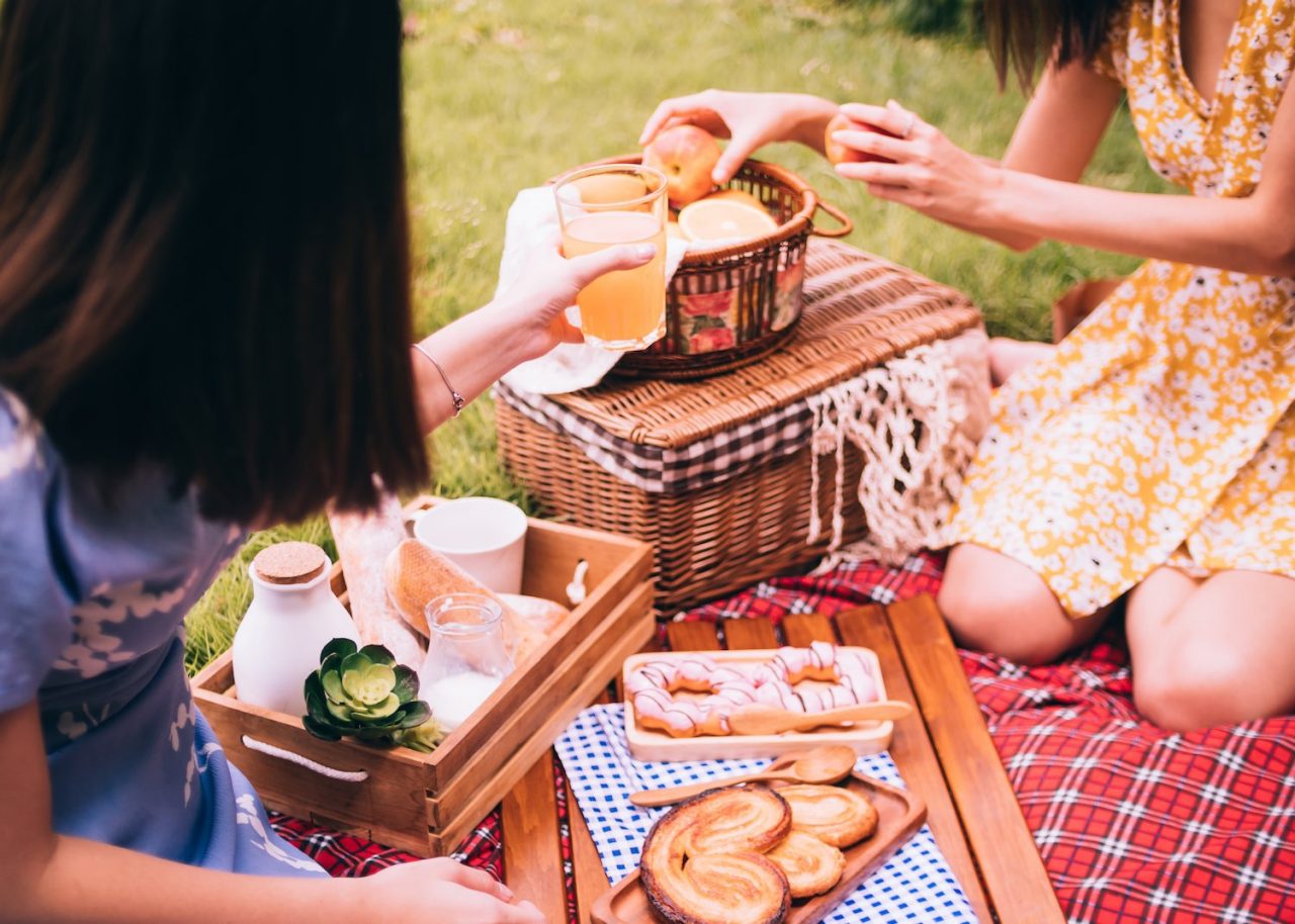 Two female friends enjoying picnic together in a park.