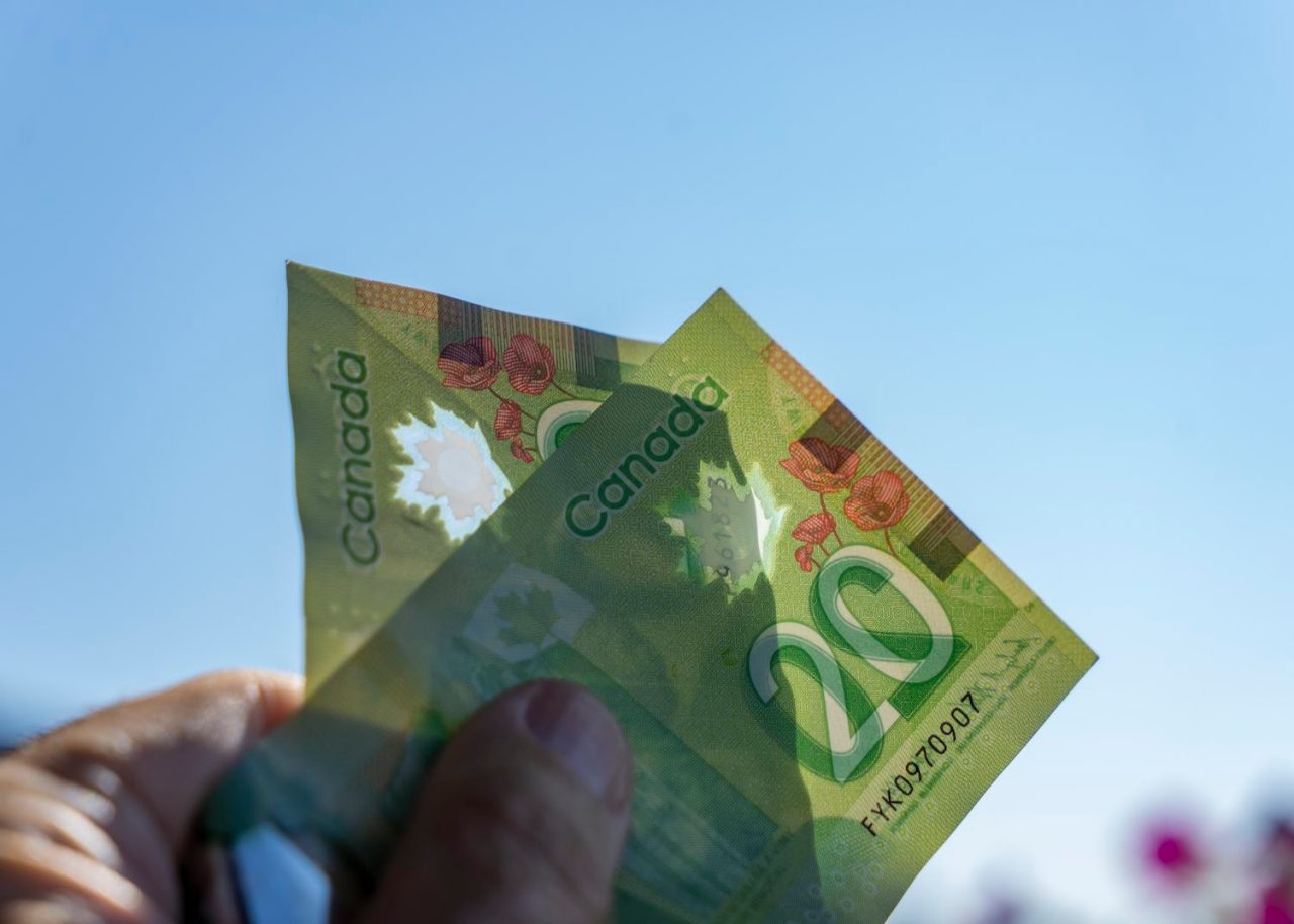 Canadian dollars held up against the sky.