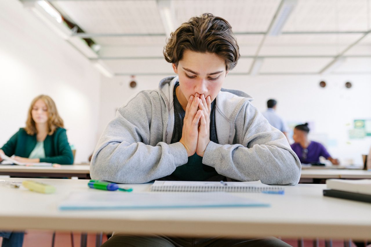 A worried high school student looking at his test paper before starting during an exam.