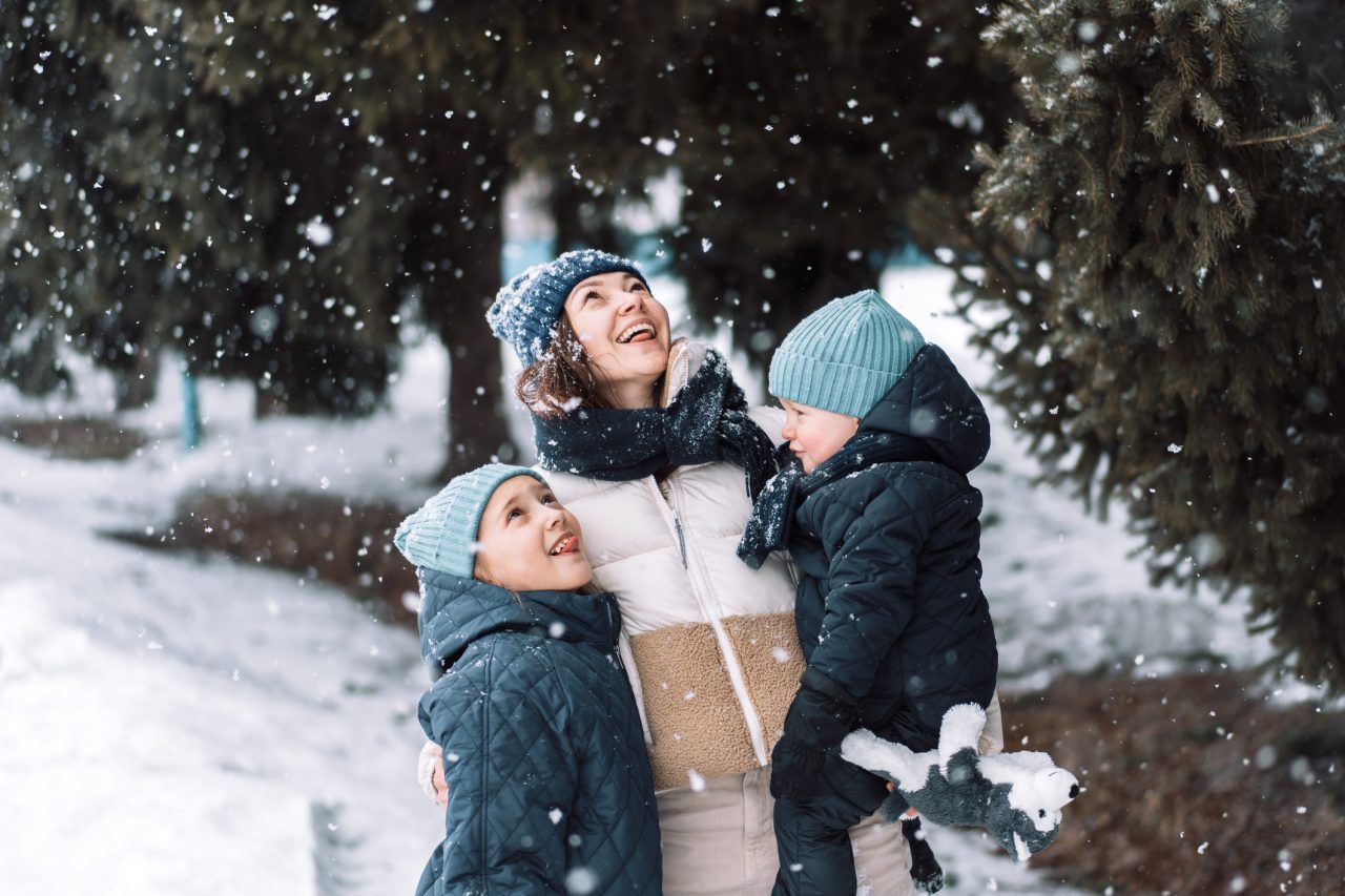 Mom with son and daughter catching snow with their hands.