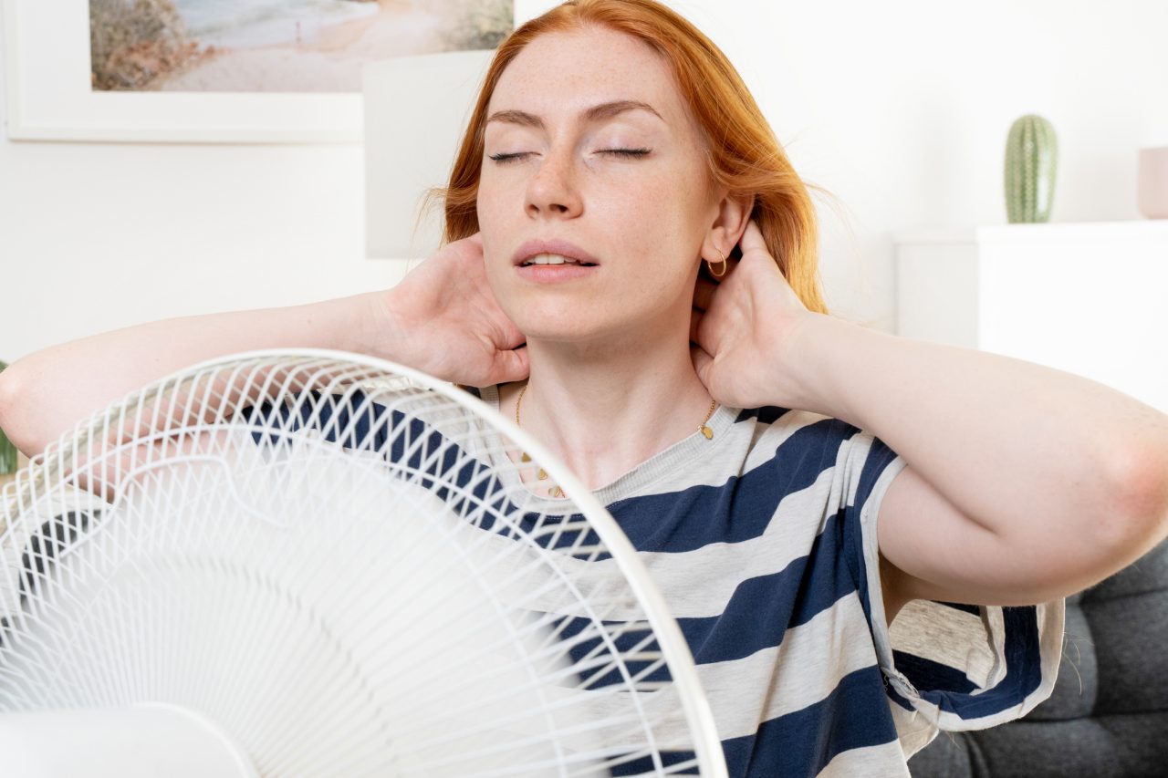 Young woman suffering summer heat wave at home