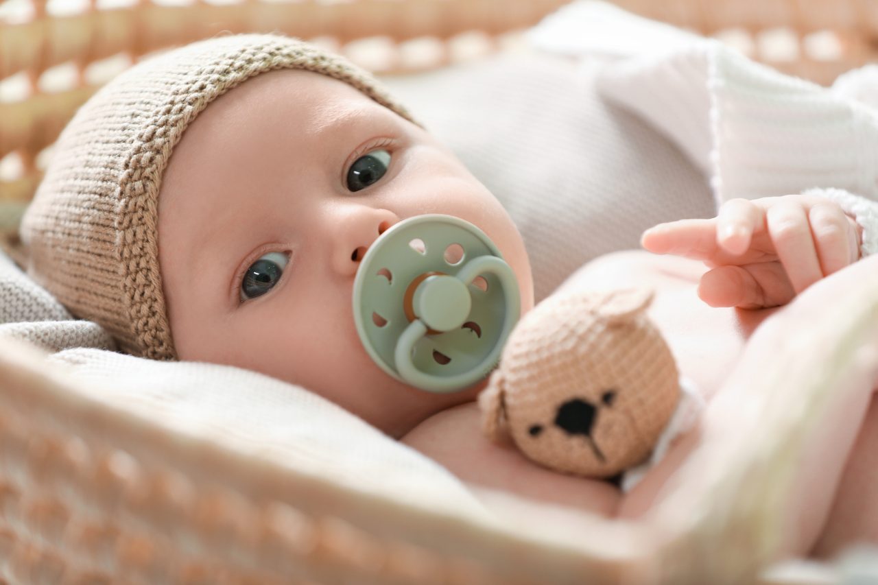 Cute newborn baby on white blanket in wicker crib, closeup