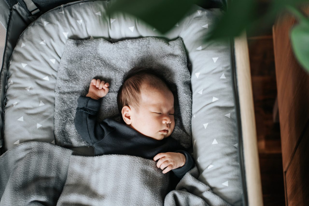 High angle shot of lovely Asian newborn baby girl sleeping soundly in the crib at home