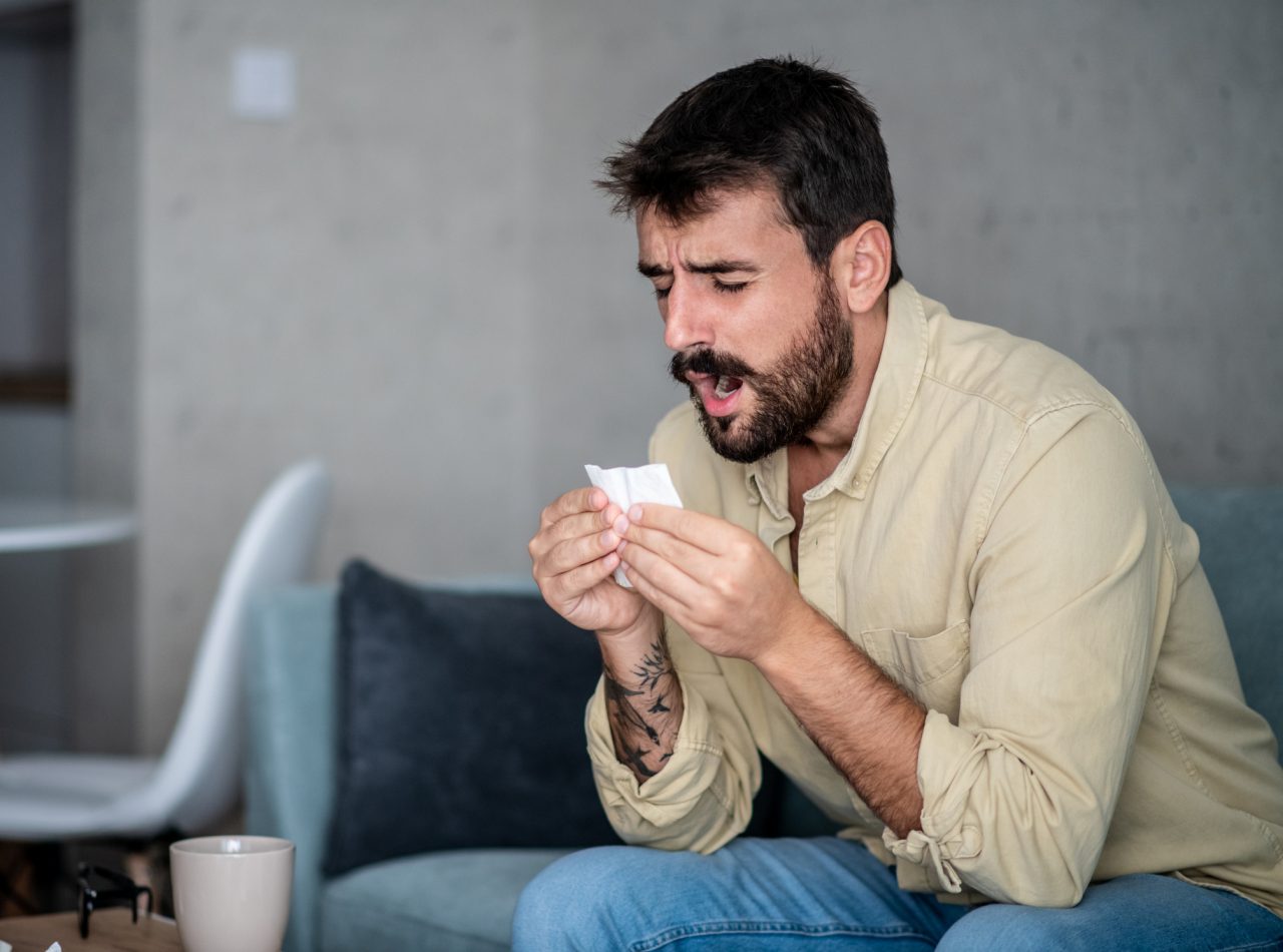 Young man started to cough and sneeze. He probably got COVID-19. Now he has to say home and drink hot tea, and try to calm down. The ending has not have to be deadly.