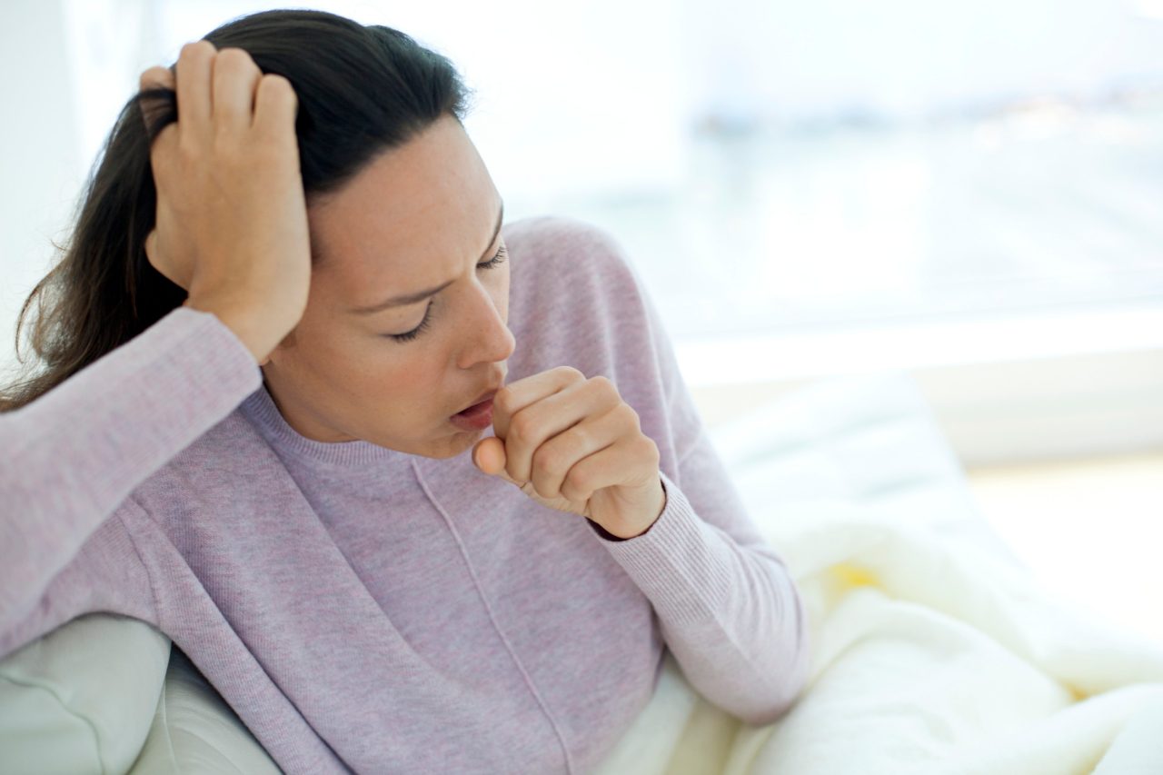 MODEL RELEASED. Young woman coughing.