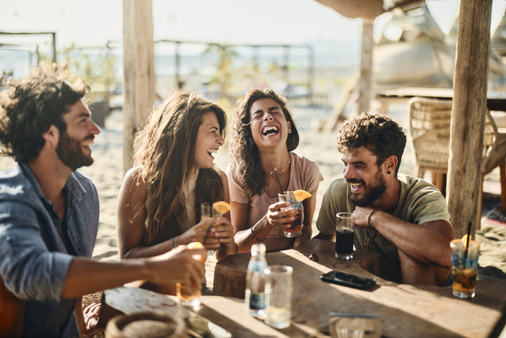 Group of cheerful friends communicating while spending a summer day in a beach cafÃ©.