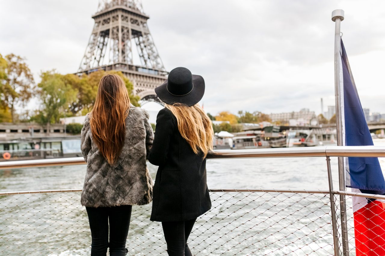 Paris, France, two female tourists taking a cruise on the Seine River with the Eiffel Tower in the background.